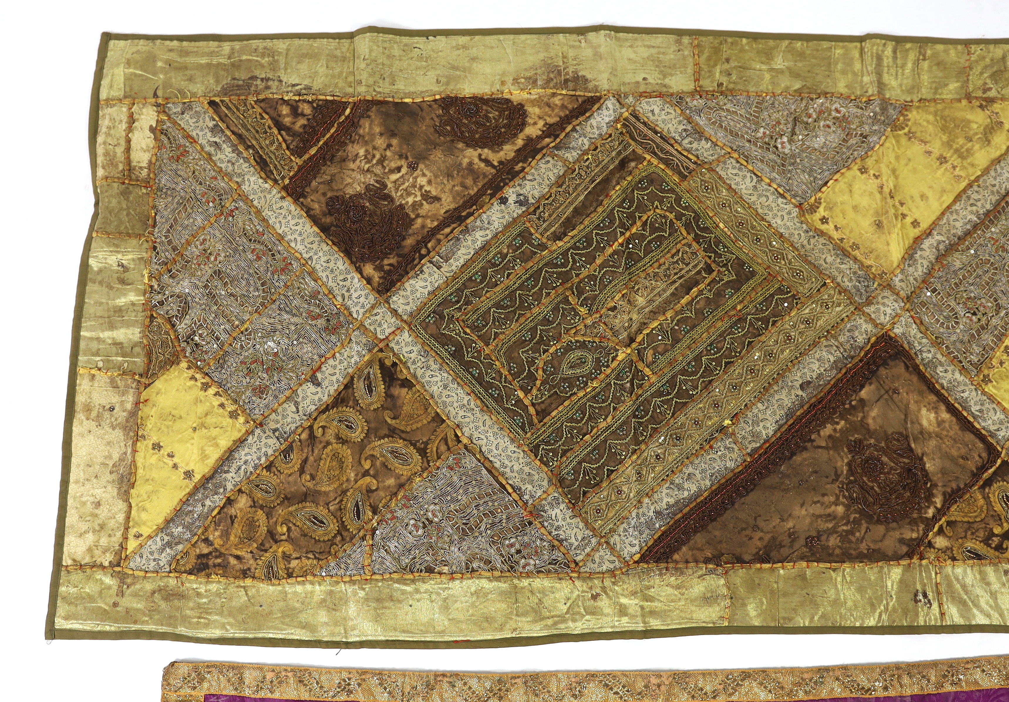 A 20th century Indian patchwork hanging, designed in golds and browns using patchwork batik, beadwork and metallic embroidery, each bordered with thick silk strands bound together, the hanging then bordered with gold met